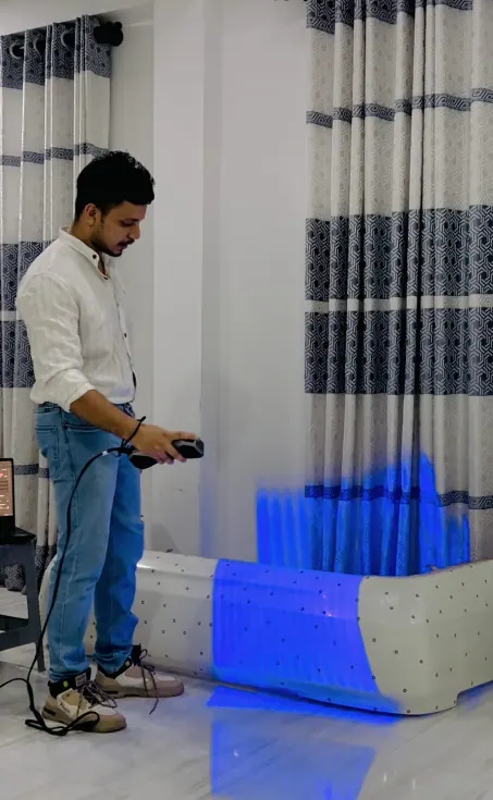 MechaCAD engineer capturing a 3D scan of a moulded part with a handheld structured-light scanner, the blue scan pattern visible across its surface