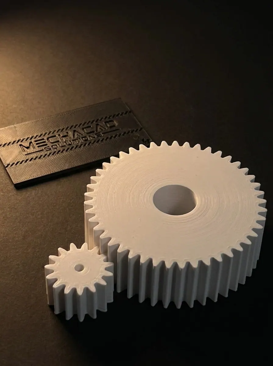 Pair of 3D printed white spur gears with a MechaCAD Solutions card for scale